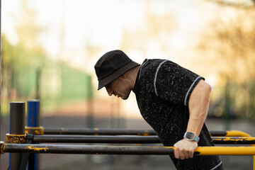 Focused individual engages in fitness training performing dips on parallel bars outdoor gym. scene...