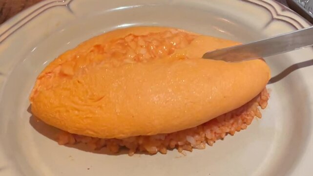Japanese Omurice Being Cut Open to Reveal Soft Scrambled Egg