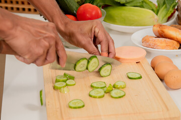 Asian man with beard sitting makes sandwich for breakfast in morning at kitchen. Male wear apron enjoy make food for health care in house,  free time in modern kitchen interior. healthy food at home.