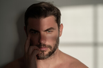 Fototapeta premium Sexy shirtless man close up portrait care of skin, isolated over white background. Charming man with perfect smooth soft skin. Spa therapy. Man, face, beauty and skincare concept.