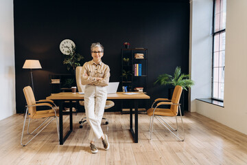 Confident smiling senior businesswoman posing in modern office, looking at camera
