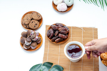 POV Of Hands Taking Hot Tea For Breakfasting With Various Sweet Snacks And Dates Fruit
