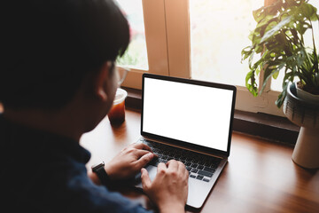Man holding smartphone with blank screen above closed laptop in cafe, perfect for digital product or app preview.