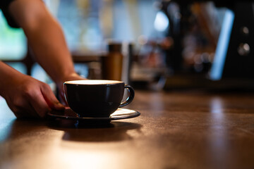 Small business entrepreneur coffee shop cafe restaurant owner concept. Barista making hot cafe latte in coffee cup serve to customer on counter bar. Waiter working part time job at coffee shop.