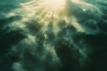 Fototapeta premium Aerial view of misty mountains with sun rays piercing through the clouds above the landscape scene