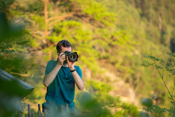 Young man taking pictures with camera in a wooded scenic area
