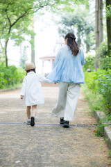 Fototapeta premium 公園で手を繋いで歩く母娘の後ろ姿