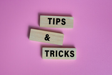 tips and tricks words on wooden blocks isolated on pink background