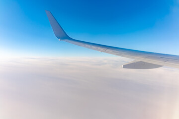 Fototapeta premium View from the airplane window at a beautiful cloudy sky and the airplane wing