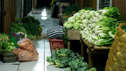 Fresh vegetables at a traditional market, including cabbage, carrots, and greens. Display of organic and simple farm produce in a local Southeast Asian setting