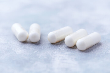 Creatine capsules on bright wooden background. Soft focus. Close up. Copy space.
