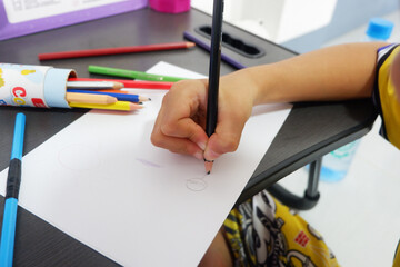 A boy's hand is practicing drawing shapes on paper.