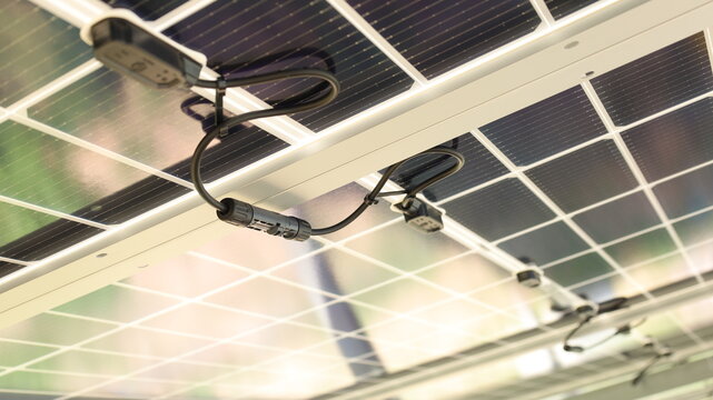 Solar cell connector. Close-up of Solar PV connector of solar cell circuit and wires under solar panel in smart farm with copy space and focus selection.