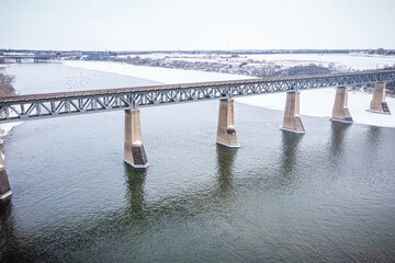 Bridge spans a river with a snowy landscape in the background