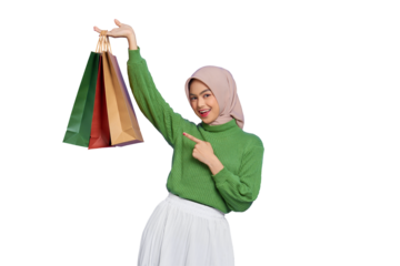 Cheerful beautiful Asian woman in green sweater pointing finger at shopping bag isolated on transparent background