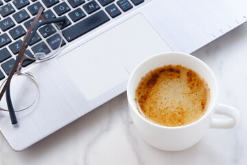 淹れたての美味しいコーヒーを飲みながら、ノートパソコンでデスクワークをしているイメージ
