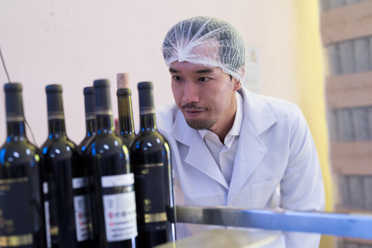 Winemaker inspecting quality the process of fermentation during manufacturing in winery factory
