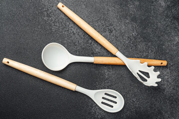 Cooking utensils arranged on a dark countertop with wooden handles