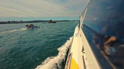 Dynamic footage from Sydney Harbour ferry cutting through waves at speed. Sunny day with passing vessels showcases ferries as vital public transport.