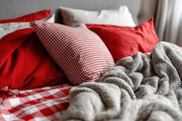 bed with red and white sheets, blankets, and pillows neatly arranged, creating a cozy atmosphere