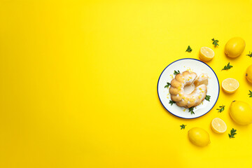 Lemon cake on plate and lemons on yellow background, space for text