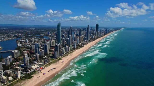 Breathtaking aerial footage of Gold Coast showcasing coastal skyscrapers, endless sandy beaches, ocean waves, and blue skies. Vibrant summer day highlights this luxurious resort city.