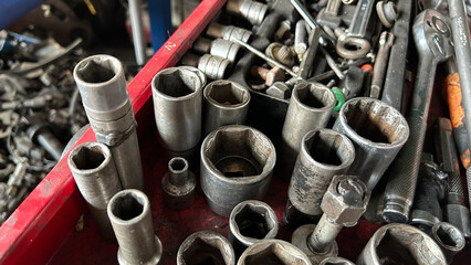 Close-up image of assorted metal sockets and wrenches in a toolbox, showcasing industrial tools and equipment.