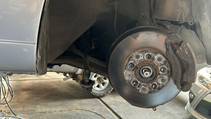 Close-up of a car disc brake during maintenance in a garage workshop, showcasing automotive repair and service.
