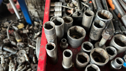 Close-up of assorted metal tools in a workshop, showcasing various socket wrenches and mechanical...