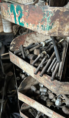 Rustic metal shelves filled with assorted industrial bolts and hardware in workshop setting.