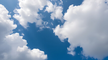 Skyward view with giant fluffy white clouds filling the frame against a backdrop of deep blue sky and smaller puffs bel