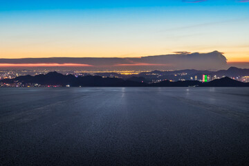 Asphalt road platform and city skyline with mountain at night