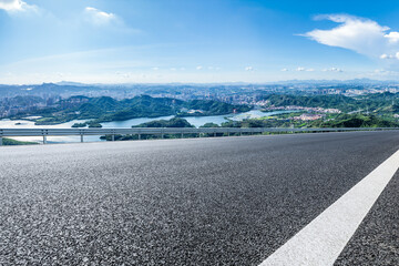 Empty square floor and city skyline with green mountain scenery under blue sky