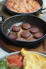 Savory dish of fried sausage and omelette on a wooden table