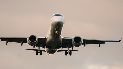 Majestic airplane gliding through the cloudy sky during sunset over the airport landscape