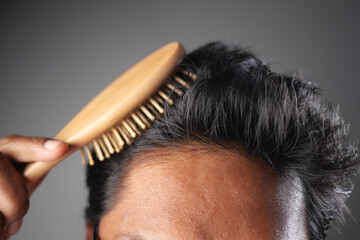 Grooming hair with a wooden brush in indoor lighting
