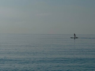 Earlier in the morning. Sea Plaid. Silhouette of a man. Man alone is floating on a SUP board. Padding
