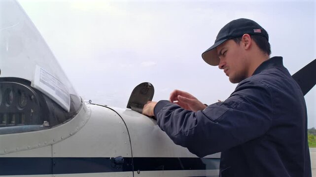 Male Pilot Checks Oil Level of Airplane Piston Engine with Dipstick