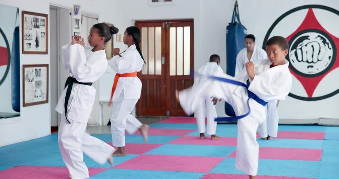 Children, learning karate and training in class with instructor for fight, fitness or self defense. Students, kids and people practice martial arts, kick and exercise for lesson with teacher in dojo