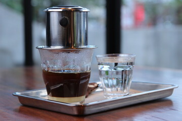 a glass of brewed black coffee with vietnam drip and a glass of water