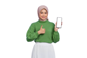 Smiling beautiful Asian woman in green sweater and hijab showing blank screen mobile phone and gesturing thumbs up isolated on transparent background