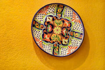 A hand painted Mexican talavera dinner plate hang on the wall.