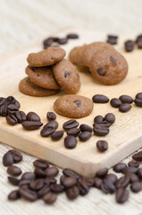 A stack of coffee chocolate chip cookies sits on a bed of coffee beans.
