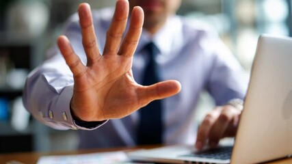 Business Man gesturing "Stop": A determined individual, working diligently on a computer in an office environment, emphatically gestures a halt, expressing a sense of urgency, and assertiveness.
