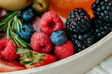 Close-up of fresh berries, rosemary, olives, and honey dip.