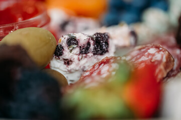 Close-up of salami slices, cheese, olives, and red jam.