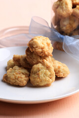 A delectable pile of golden-brown cheese sago cookies with a slightly irregular, rustic texture is presented on a white plate