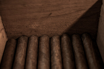 Rolled cigars stacked in wood box