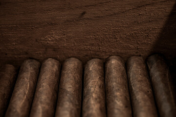 Rolled cigars lined up in a wood box