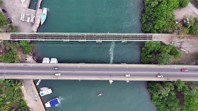 La Romana, Dominican Republic, hovering above  "Charles Bluhdorn" Bridge - a Car and railway bridge - across "Rio Dulce", while cars crossing the bridge, - 4K aerial top view video footage 